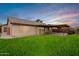 Back exterior of house with grassy yard and patio at sunset at 13292 W Statler St, Surprise, AZ 85374