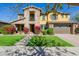 Charming two-story home with a stone and stucco exterior, a well-manicured lawn and vibrant flowerbeds at 4813 S Quantum Way, Mesa, AZ 85212