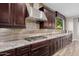 Gourmet kitchen with stainless steel range hood, granite countertops, and custom dark wood cabinets at 4813 S Quantum Way, Mesa, AZ 85212