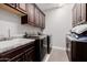 Beautiful laundry room with gray tile floor, granite countertops, and cherry cabinets at 4813 S Quantum Way, Mesa, AZ 85212