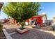 Backyard with paved patio, landscaping, and a large tree at 7135 W Heatherbrae Dr, Phoenix, AZ 85033