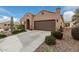 Front view of a tan house with a two-car garage and drought-tolerant landscaping at 8047 W Cinder Brook Way, Florence, AZ 85132