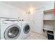 Bright laundry room, featuring washer, dryer, shelving and tile floor at 122 W Washington Ave, Gilbert, AZ 85233