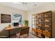 Bright home office with rustic wooden desk, shelving unit, and comfortable chair at 19241 N Emerald Cove Way, Surprise, AZ 85387