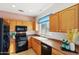 View of kitchen with wood cabinets, black appliances, and tile flooring at 19241 N Emerald Cove Way, Surprise, AZ 85387