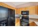 Close up of kitchen with wood cabinets and black appliances at 19241 N Emerald Cove Way, Surprise, AZ 85387