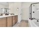 Bathroom featuring a soaking tub, glass-enclosed shower, and double sink vanity at 19724 W Palo Verde Dr, Litchfield Park, AZ 85340