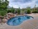 Kidney-shaped pool with waterfall feature and desert landscaping at 2164 W Muirfield Dr, Anthem, AZ 85086