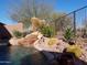 Peaceful pool area with waterfall, rocks, and desert plants at 2164 W Muirfield Dr, Anthem, AZ 85086