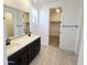 Bathroom featuring double vanity, large mirror, and walk-in closet access at 22311 W Monona Ln, Surprise, AZ 85387