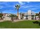 Tan house with a grassy lawn, palm tree, and attached garage at 10934 E Becker Ln, Scottsdale, AZ 85259