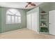 Light green bedroom with arch window, custom shelves, closet, neutral carpet, and a ceiling fan at 15237 S 19Th Way, Phoenix, AZ 85048