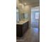 Bathroom featuring double vanity with framed mirrors, tile floor, and entrance to the main bedroom at 22319 W Monona Ln, Surprise, AZ 85387