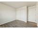 Bedroom featuring wood-look tile flooring, closet with sliding doors and a window overlooking the desert landscape at 25603 W Hedgehog Rd, Wittmann, AZ 85361