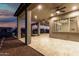 Spacious covered patio with ceiling fans overlooking a well-maintained backyard at dusk at 42085 W Morning Glory Way, Maricopa, AZ 85138
