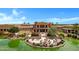 Exterior view of the clubhouse featuring a patio with seating, landscaping, and a tranquil pond setting at 42085 W Morning Glory Way, Maricopa, AZ 85138