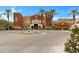 Elegant multi-colored community building with a fountain, palm trees, and manicured landscaping in a circular driveway at 42085 W Morning Glory Way, Maricopa, AZ 85138