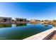 Peaceful lakefront view with reflection of homes and lush greenery at 42085 W Morning Glory Way, Maricopa, AZ 85138