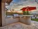 Outdoor kitchen with grill, bar seating, and red umbrella at 44622 N Sonoran Arroyo Ln, New River, AZ 85087