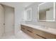 Bright bathroom with dual sink vanity, wood cabinets, illuminated mirrors and white tile floors at 5000 N Camelback Ridge Dr # 301, Scottsdale, AZ 85251