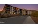 Exterior view of a modern multi-story residential building with evening lighting on a desert landscape at 5000 N Camelback Ridge Dr # 301, Scottsdale, AZ 85251