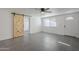 Bright living room featuring gray tile floors, a barn door, and ceiling fan at 8230 W Monterey Way, Phoenix, AZ 85033