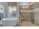 Luxurious bathroom with a soaking tub, large window, and a glass-enclosed shower with seat at 31023 N 117Th Dr, Peoria, AZ 85383