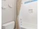 Bright bathroom with a white tiled tub and a patterned shower curtain at 31023 N 117Th Dr, Peoria, AZ 85383