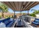 Covered outdoor kitchen, including BBQ and sink, sits beside comfortable outdoor seating under a pergola at 31023 N 117Th Dr, Peoria, AZ 85383
