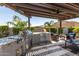 Outdoor BBQ kitchen and dining area under a pergola with tile flooring at 31023 N 117Th Dr, Peoria, AZ 85383