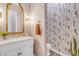 Sophisticated powder room featuring designer wallpaper, marble countertop, and gold fixtures at 31023 N 117Th Dr, Peoria, AZ 85383
