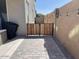 Private backyard with a paved patio, wood gate, and exterior wall at 42206 W Capistrano Dr, Maricopa, AZ 85138
