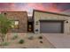 Modern home exterior with stone accents and landscaped front yard at sunset at 12411 E Troon Vista Dr, Scottsdale, AZ 85255