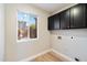 Bright laundry room features wood-look floors, black cabinets, and a window at 15550 N Frank Looyd Wright Blvd # 1057, Scottsdale, AZ 85260