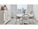 Bright dining room with white table and chairs, farmhouse-style cabinet, and window at 36085 W Prado St, Maricopa, AZ 85138