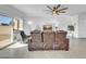 Living room with brown leather reclining furniture, ceiling fan, and sliding glass doors at 36085 W Prado St, Maricopa, AZ 85138