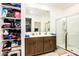 Double vanity bathroom with a shower and linen shelves at 40634 W Hillman Dr, Maricopa, AZ 85138