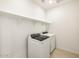 Modern laundry room with a full-size washer, dryer, and open shelving at 16029 W Desert Hollow Dr, Surprise, AZ 85387