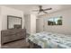 Neutral bedroom featuring wood-look floors, ceiling fan, window view, and light wood dresser with large mirror above at 4124 N 105Th Ln, Phoenix, AZ 85037