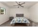 Bright bedroom featuring wood-look flooring, ceiling fan, a window view and light wood bed frame with upholstered headboard at 4124 N 105Th Ln, Phoenix, AZ 85037