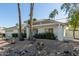 Landscaped front yard with a white single story home with a metal roof at 7489 E Windrose Dr, Scottsdale, AZ 85260