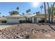 White single story home with metal roof, desert landscaping, and a two car garage at 7489 E Windrose Dr, Scottsdale, AZ 85260