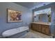 Spa-like bathroom with a large soaking tub and wooden vanity at 7546 E High Point Dr, Scottsdale, AZ 85266