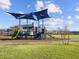 Community playground with slides, climbing structures, and shade, on a grassy area under a blue sky at 17803 W Elm St, Goodyear, AZ 85395