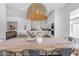 Rustic dining table with woven light fixture and kitchen views at 21961 E Via De Arboles St, Queen Creek, AZ 85142