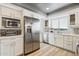 Bright kitchen features white cabinets, stainless steel refrigerator, and wood-look floors at 8008 E Del Rubi Dr, Scottsdale, AZ 85258