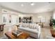 Bright living room featuring a white sofa, tile floors, and an open layout to the kitchen at 12935 W Lone Tree Trl, Peoria, AZ 85383