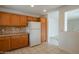 View of kitchen featuring oak cabinets, granite counters, white appliances, and tile floor at 15909 W Elm St, Surprise, AZ 85374