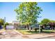 Charming single-story home with a brick exterior, solar panels, lush lawn, mature tree, and inviting front porch at 2157 W Mulberry Dr, Phoenix, AZ 85015