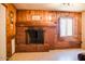 Brick fireplace in a wood paneled living room with large window at 2157 W Mulberry Dr, Phoenix, AZ 85015